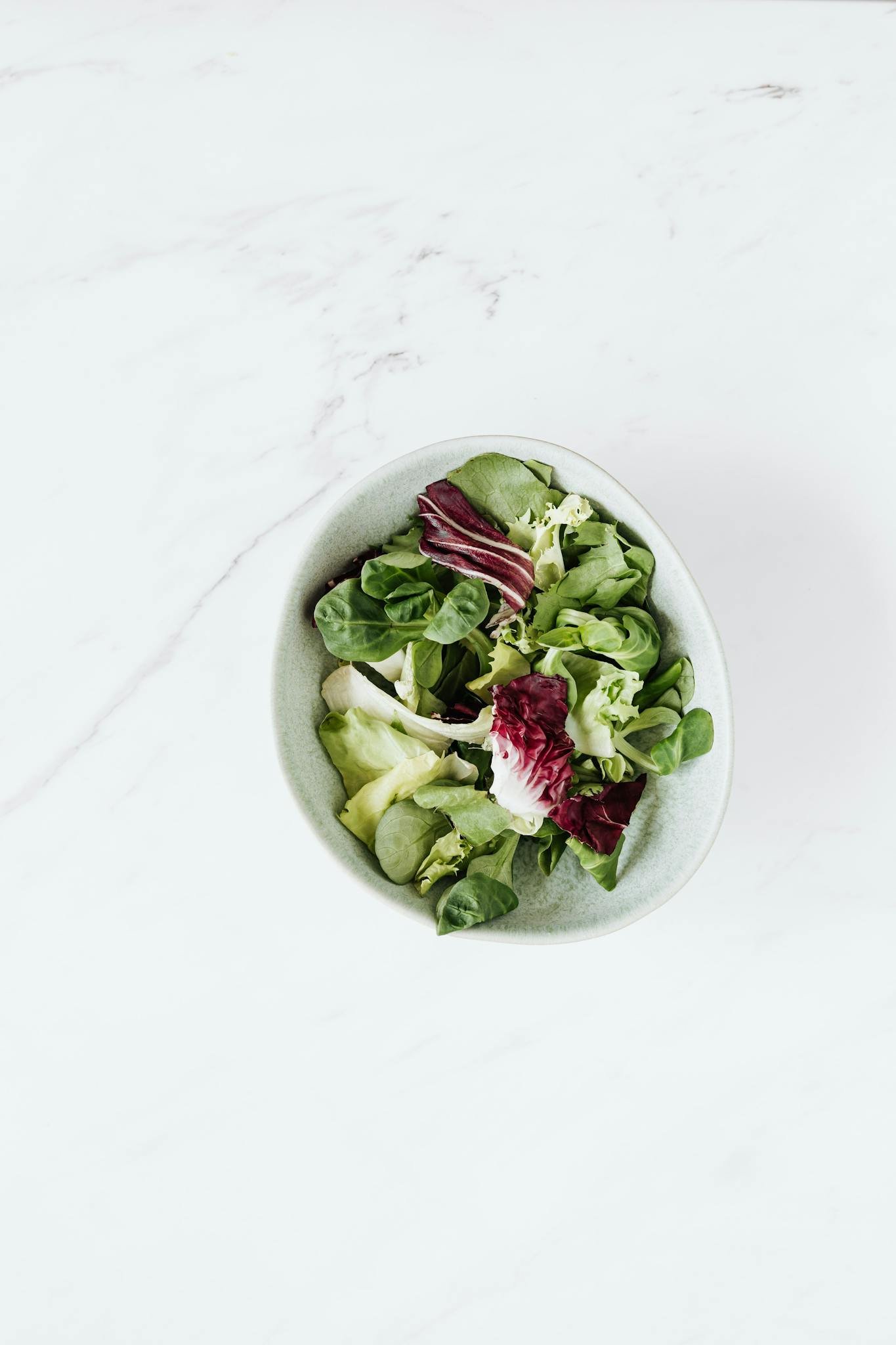 Top view of bowl with mix of salads placed on table